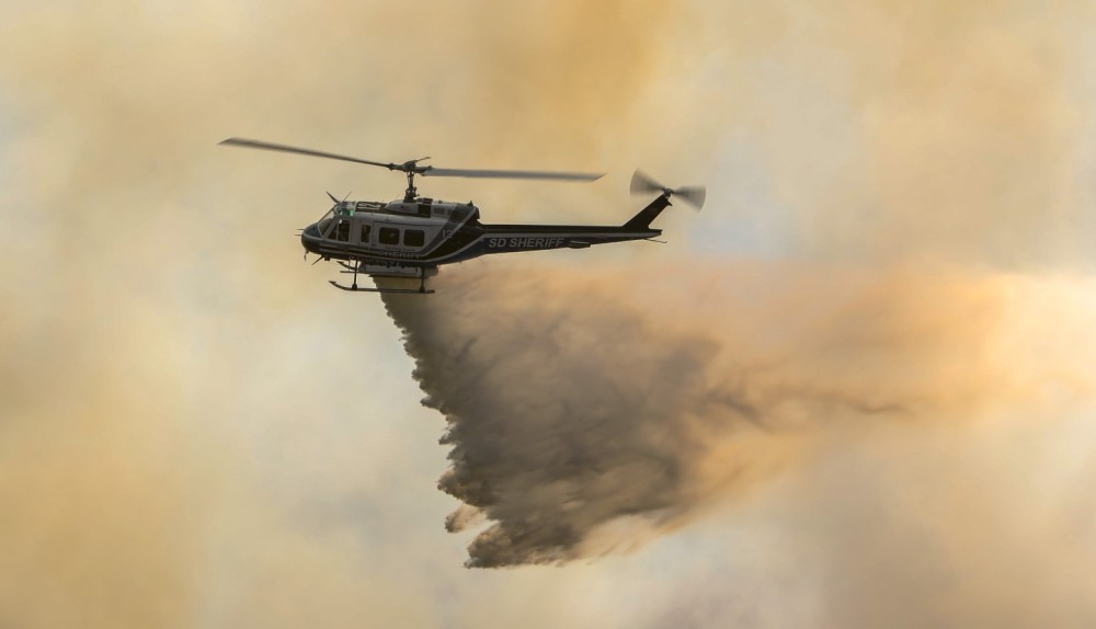 A rapidly spreading wildfire near Campo, CA sparks a multi-agency wildland response to extinguish the Posta 3 Fire from encroaching 450-acres, as a Bell 205 helicopter from the San Diego County Sheriff's Department lays waste to the flames below.