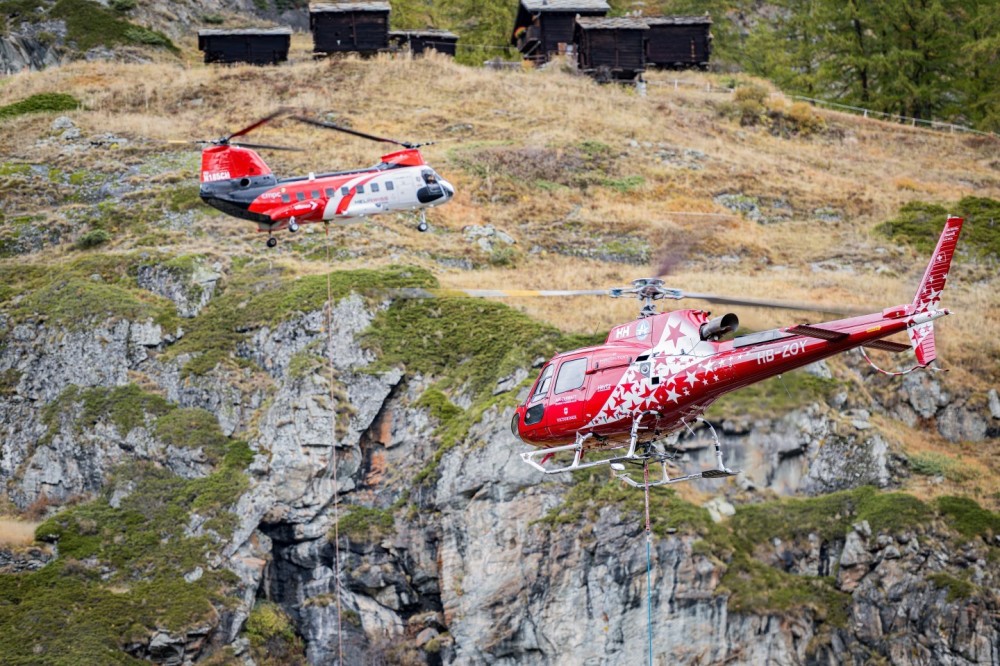 Air Zermatt HB-ZOY / Columbia 107-II Vertol. Helicopter sling load (HESLO) operations in a village require careful planning, skilled crews, and a focus on safety and precision to successfully carry out tasks in an urban