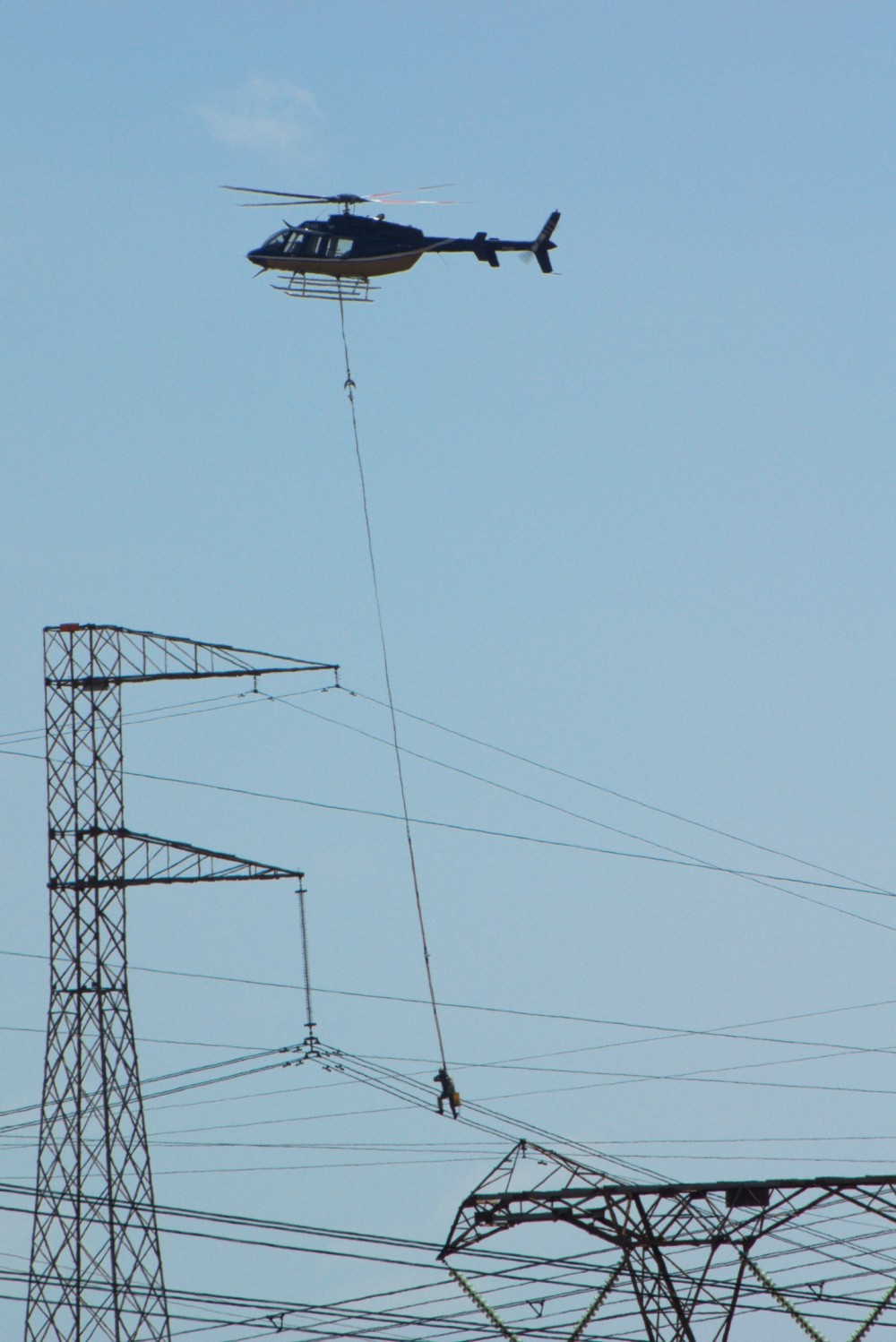 Eskom South Africa Bell 407 delivering a linesman onto a DC High Voltage line from the Cahora Bassa hydro electric station to the Apollo DC to AC station at Rietvlei south of Pretoria, South Africa