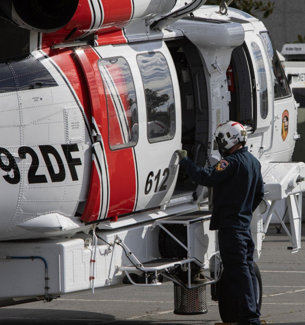 A crew chief assigned to CAL FIRE Boggs Mountain Helitack Base in Lake County, CA, communicates with the pilot's during shutdown procedures after arriving at the Anaheim Convention Center in Anaheim, CA for the 2024 HAI Heli-Expo.