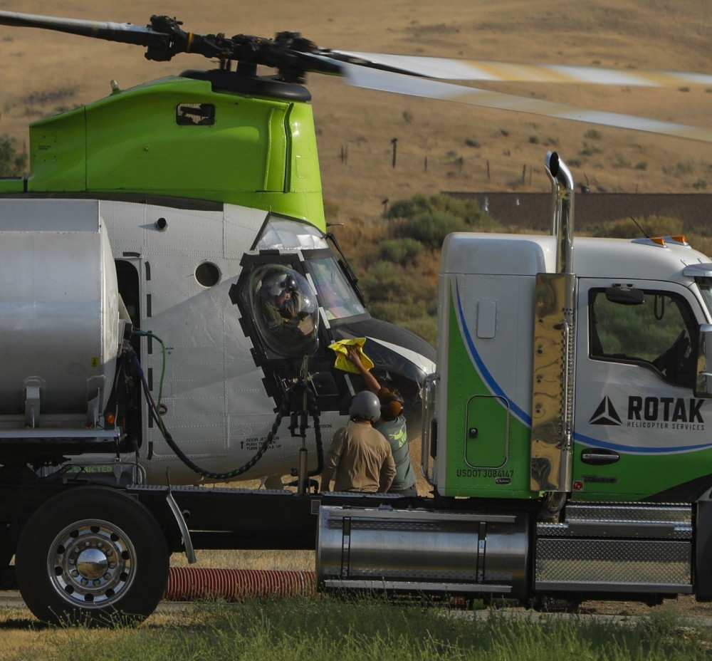 While a ROTAK CH-47 Helitanker assigned to the White Fire in Kern County (CA) hot fuels, a crew member wipes the cockpit window, clearing the ash build up that obstructs the pilot's vision.