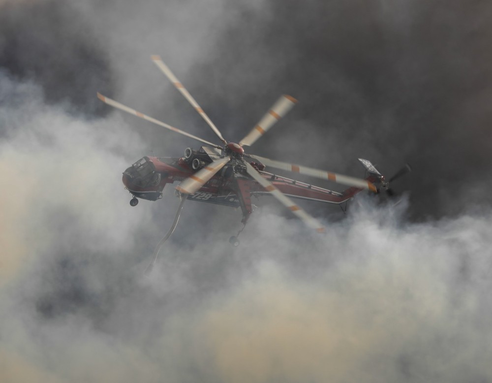 San Diego Gas & Electric's Helitanker 729 rises from the ashes after making numerous water drops on the large Posta 3 Fire off Old Hwy 80 near Campo, CA.