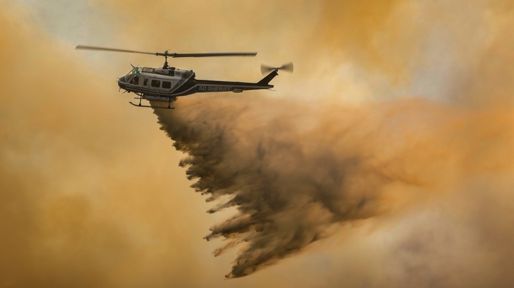 A rapidly spreading wildfire near Campo, CA sparks a multi-agency wildland response to extinguish the Posta 3 Fire from encroaching past 450-acres, as a Bell 205 helicopter from the San Diego County Sheriff Department's ASTREA Unit lays waste to the flames below.