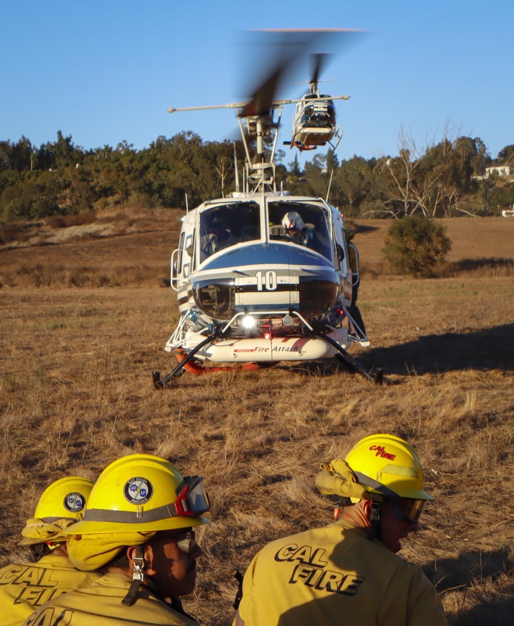 As Copter 10 of the San Diego County Sheriff Department's ASTREA Unit sits on the deck, Copter 12 approaches from behind in a staggered position to the LZ, grabbing the last CAL FIRE San Diego Gillespie Helitack crew at the end of the Garden Fire in Fallbrook, CA.