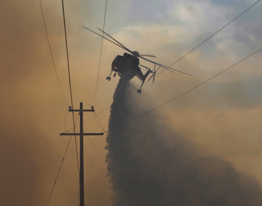 Helitanker 729 dumps its heavy load of water on a dangerous spot fire under a few high voltage power lines off Old Highway 80, during a large rapidly spreading & wind driven vegetation fire near Campo, CA.