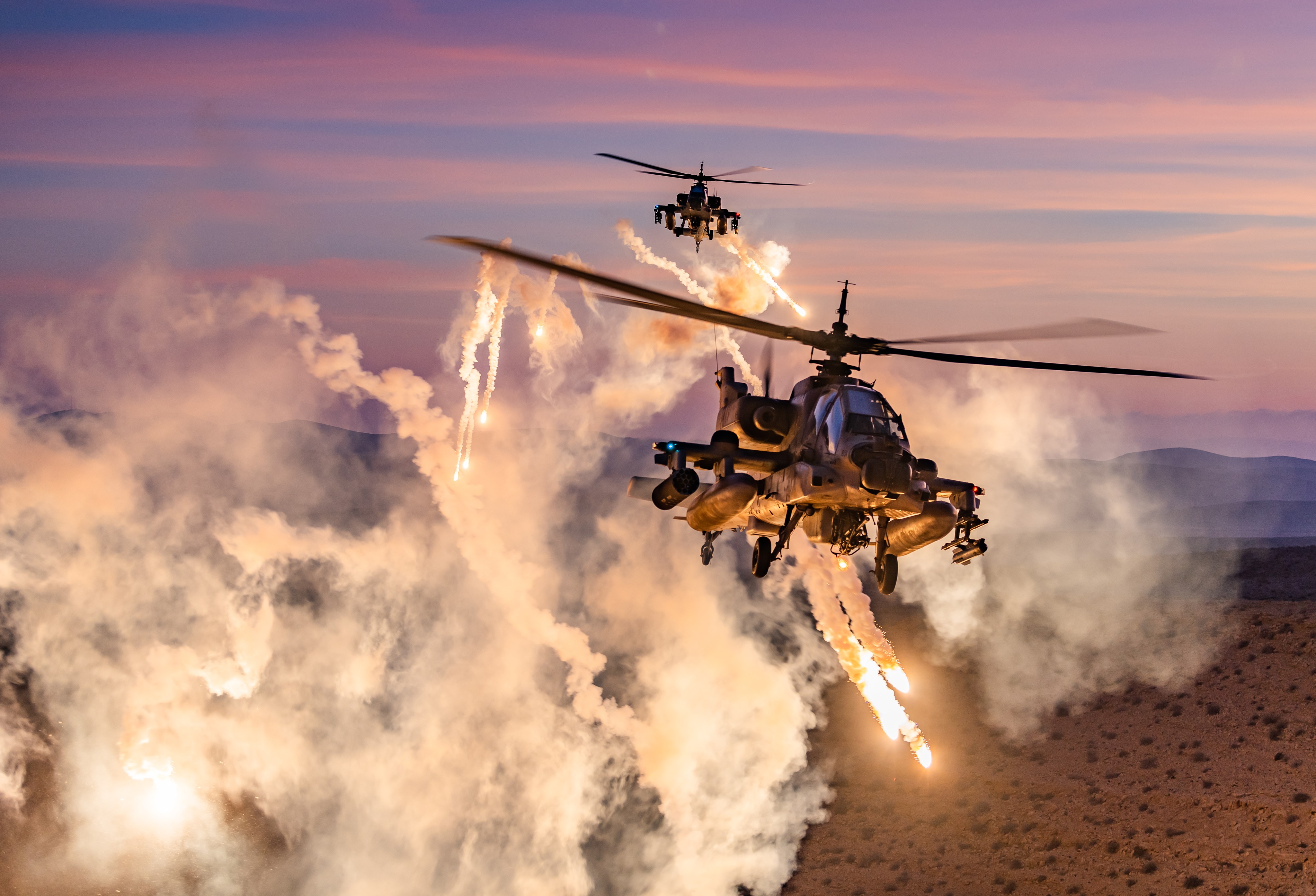 Israeli Air Force pair of an Ah 64's helicopters from the &quot;magic touch&quot; Squadron flying in a close formation and conducting a
flares release during an amazing desert sunset