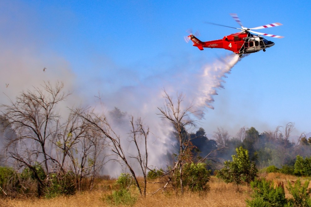 Los Angeles City FD Fire-4 makes a drop on a brush fire in the Sepulveda Basin on June 28, 2024.  This fire began in a homeless encampment and included exploding propane tanks, so water drops were more appropriate than hand lines.