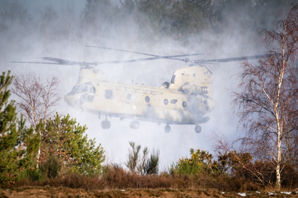 A Boeing CH-47F Chinook military transport helicopter of the Royal Netherlands Air Force is performing touch and go's in the snow at a low flying area.