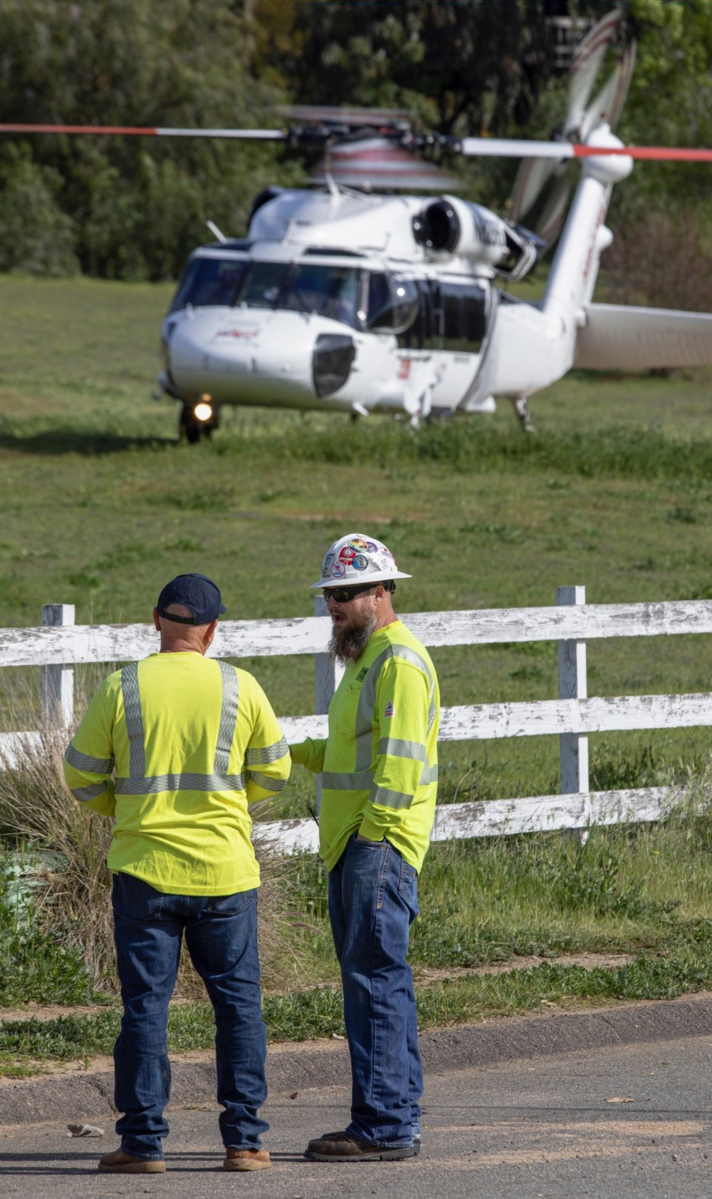 A construction crew assigned to a helicopter pole setting operation in the backcountry of San Diego County, CA on March 9, 2024, wait as a High Performance Helicopters HP-60A finishes a fuel stop before returning to its home base in La Verne, CA.