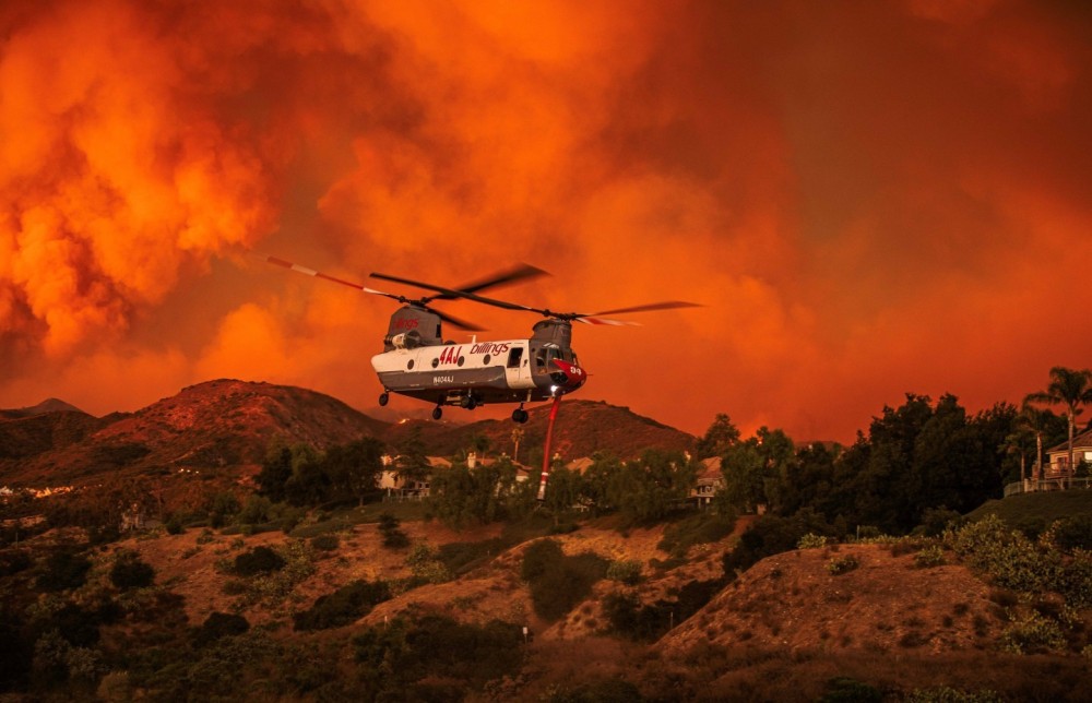 Billings Flying Services CH-47 Chinook making numerous runs during the Airport fire in Orange County California. The sunset caused the orange glow of the smoke. This Chinook was working the fire for numerous days. The exact location of this photo was off of Dove Canyon Road. There were a few other aircraft that were getting water from this location as well as the Oso lake. The fire has burned over 23,000 acres and spread int Riverside county. Currently the fire is at 88% containment. The fire started in the Trabuco Canyon area by county workers.