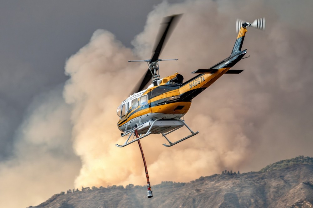 Heaps Peak Helitack BellUH-1V Iroquois heads towards the Line Fire in Highland, California after picking up water from Crafton Hills Reservoir. The sunlight was diffused by the smoke-filled sky, so the light produced was very soft and warm and really brought out the background.