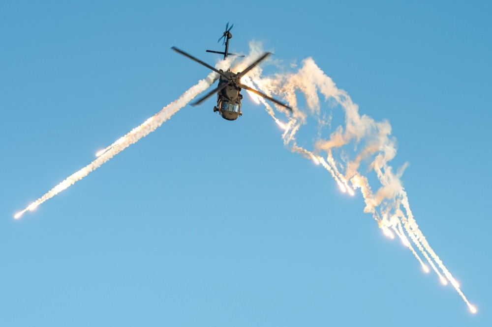 A Sikorsky UH-60 Black Hawk military helicopter from the 2nd Helicopter Squadron of the Swedish Air Force is using flares during a demonstration at the Sanicole sunset airshow.