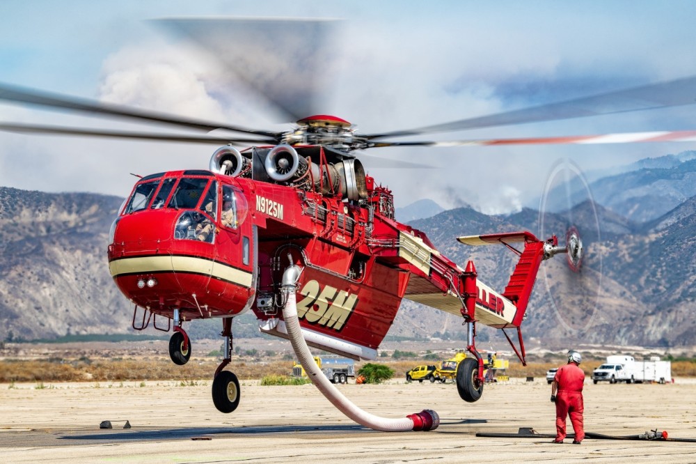 Siller’s Skycrane lifts off at Redlands Municipal Airport, California as the pilot and aircraft mechanic check to make sure everything looks ok. The fire in the background is the Line Fire in the San Bernardino National Forest.